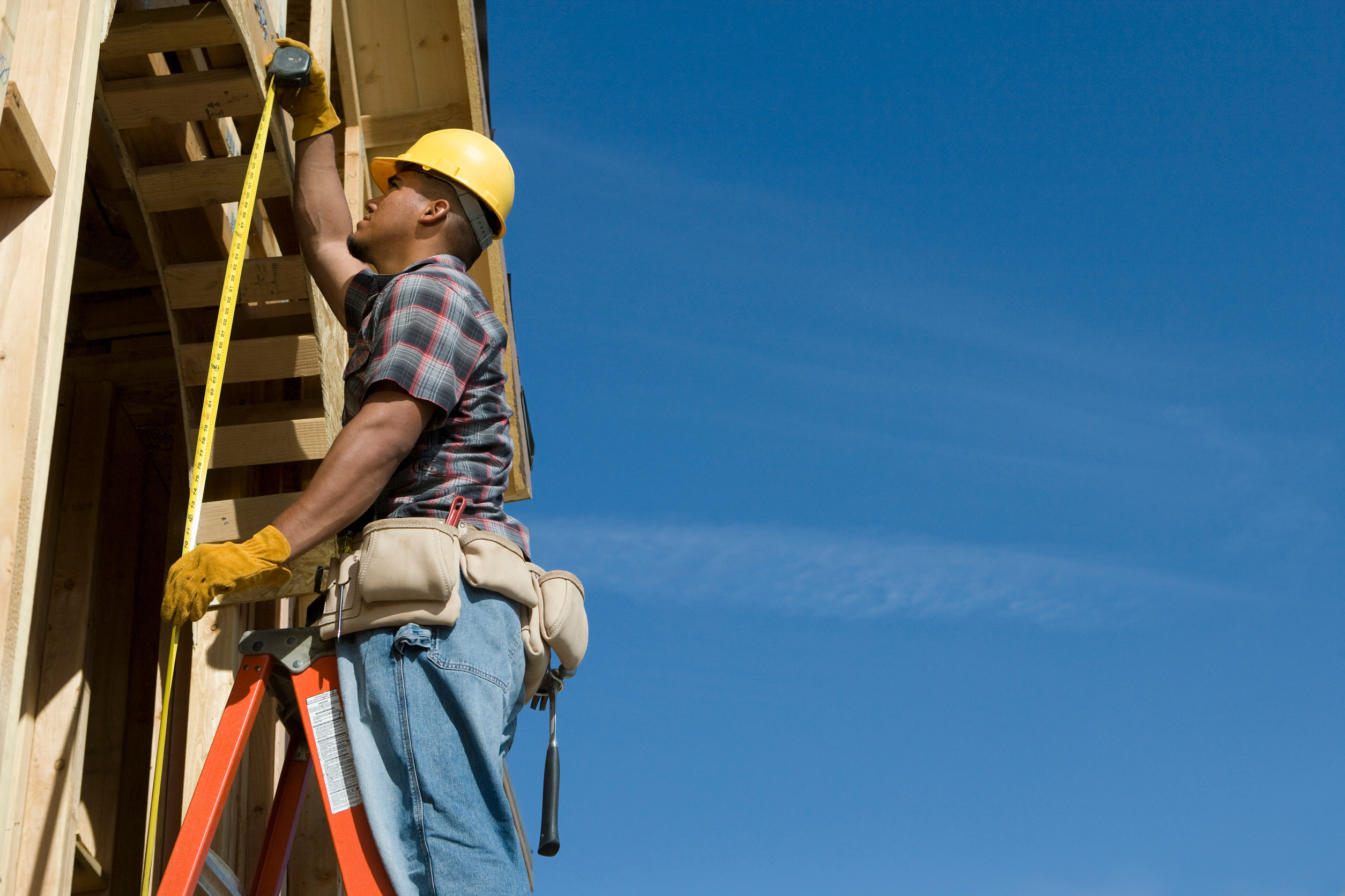 Construction worker measuring half constructed doorway with tape measure